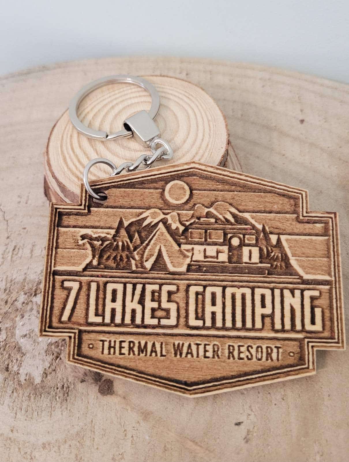 Wooden keychain with '7 Lakes Camping' design on a wooden surface