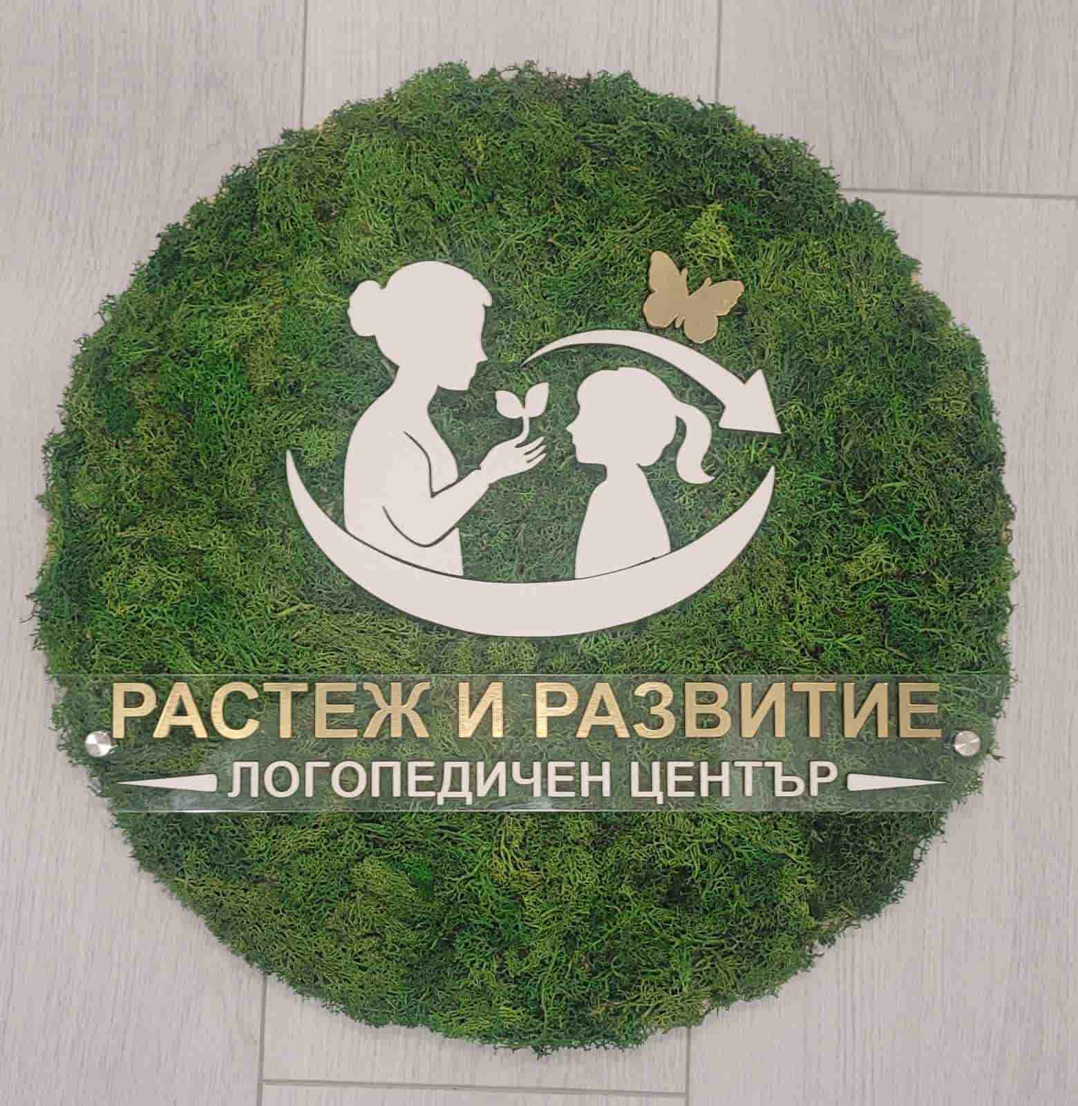 Moss-covered sign with a logo and text on a wooden floor