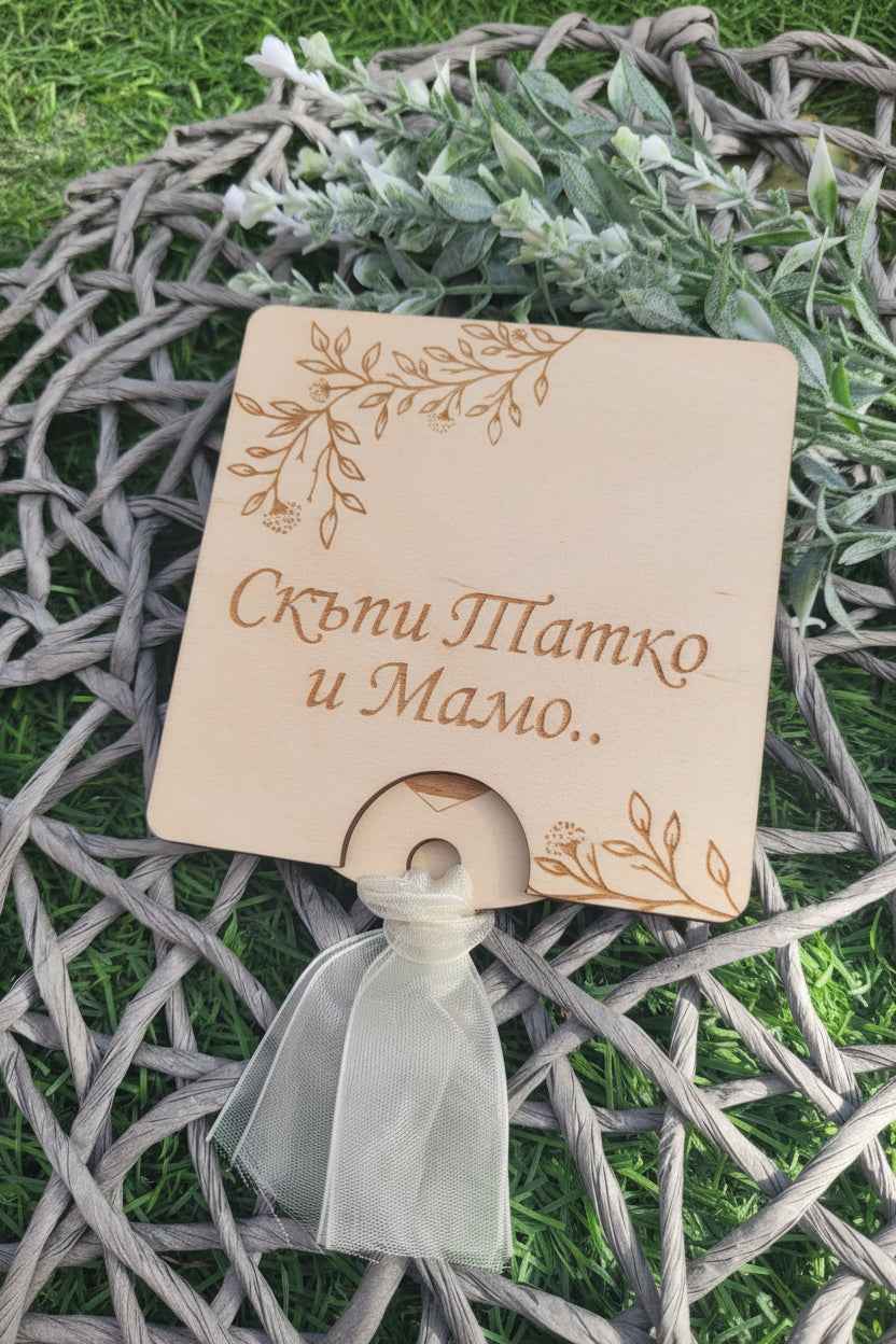 Wooden card with decorative ribbon on a textured surface with greenery