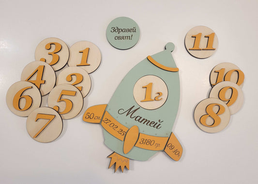Wooden baby milestone card with numbers and a baby illustration on a white background