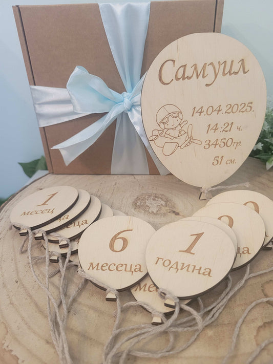 Wooden baby milestone cards with numbers and text, tied with a ribbon, on a light blue background.